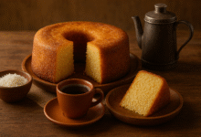 Bolo de mandioca da roça servido sobre mesa de madeira com café coado, evocando lembranças do interior.